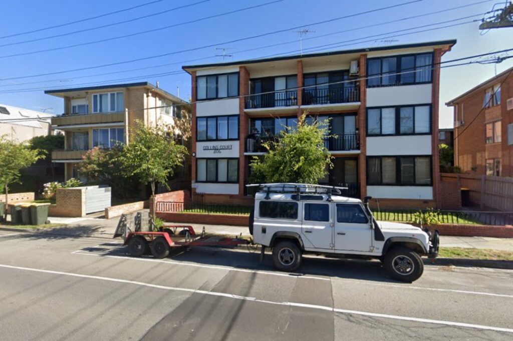 Front view of Collins Court apartment complex at 306 Inkerman Street in St Kilda East, Melbourne, showing a three-story residential building with balconies, parked vehicles, and a brick facade.